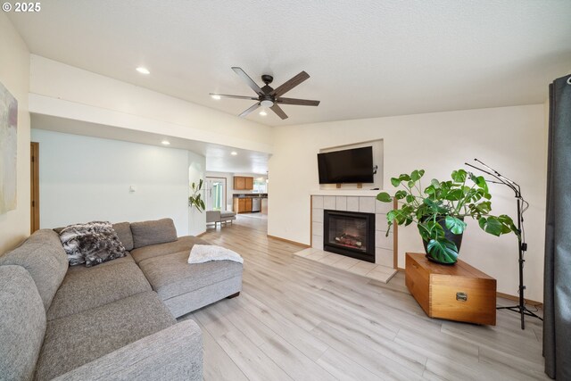 living area with a fireplace, a ceiling fan, baseboards, recessed lighting, and light wood-type flooring