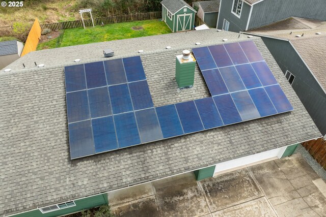 single story home featuring a garage, fence, a front yard, roof mounted solar panels, and concrete driveway