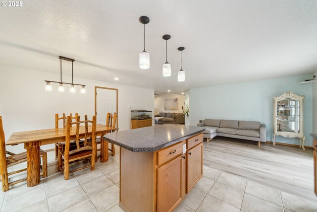 kitchen featuring pendant lighting, dark countertops, open floor plan, a center island, and light tile patterned floors