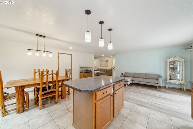 35363 Bayside Gardens Rd, Nehalem, OR 97131 - kitchen featuring dark countertops, open floor plan, light tile patterned floors, a kitchen island, and decorative light fixtures