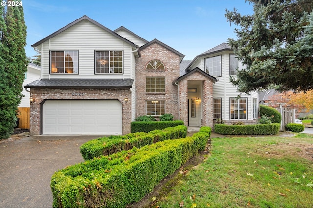 traditional home with fence, driveway, a front lawn, a garage, and brick siding