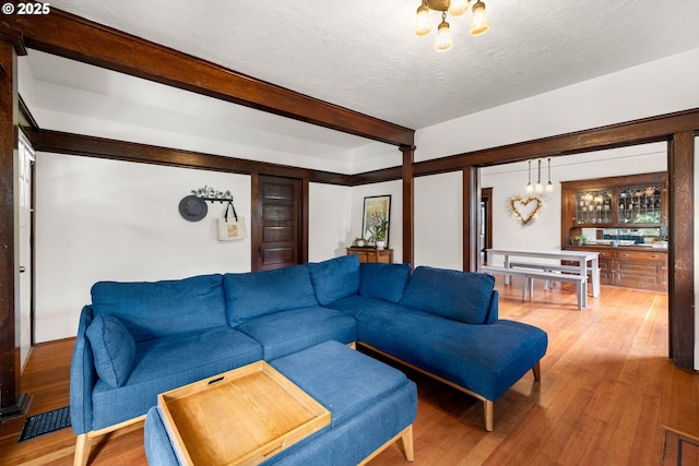 3113 SE Main St, Portland, OR 97214 - living area with a chandelier, wood finished floors, beamed ceiling, and a textured ceiling