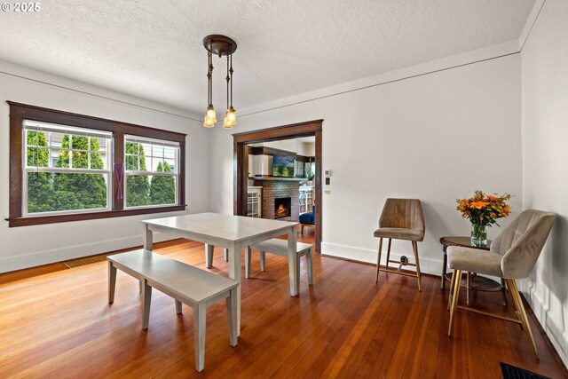 3113 SE Main St, Portland, OR 97214 - dining area with a brick fireplace, baseboards, a textured ceiling, and wood finished floors