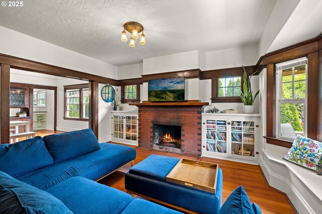 3113 SE Main St, Portland, OR 97214 - living room with wood finished floors, a fireplace, a textured ceiling, and healthy amount of natural light