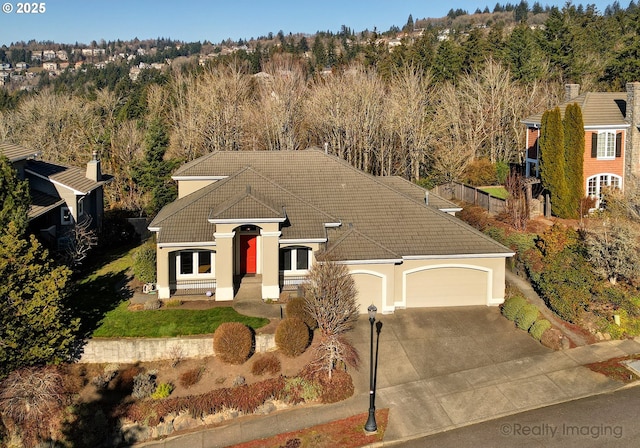 ranch-style house with an attached garage, a tile roof, driveway, and stucco siding