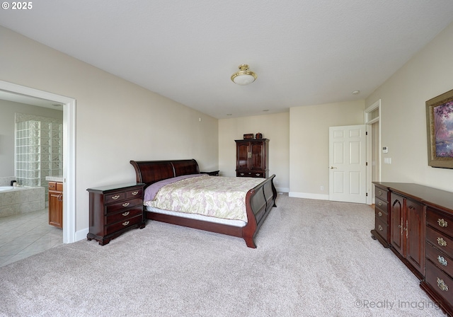 bedroom with baseboards, connected bathroom, and light colored carpet