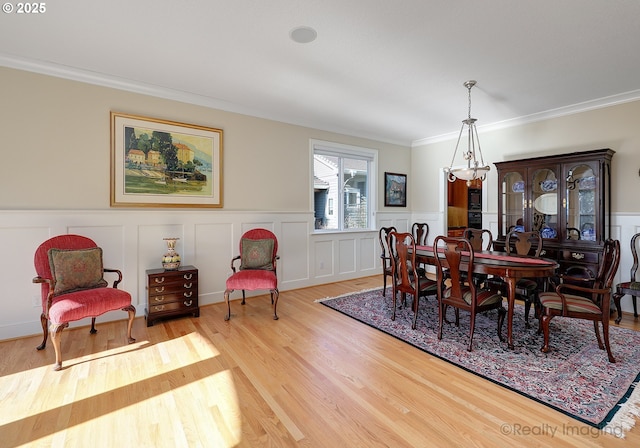 dining room featuring crown molding, a decorative wall, and wood finished floors