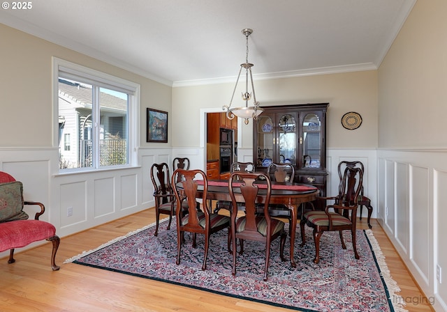 dining room with wainscoting, crown molding, and wood finished floors