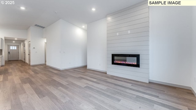 unfurnished living room with recessed lighting, a large fireplace, visible vents, baseboards, and light wood finished floors