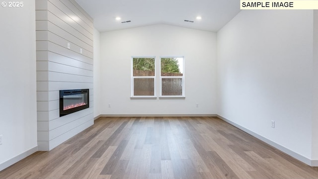 unfurnished living room featuring light wood-style flooring, a large fireplace, visible vents, baseboards, and vaulted ceiling