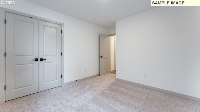 unfurnished bedroom featuring baseboards, a closet, and light colored carpet