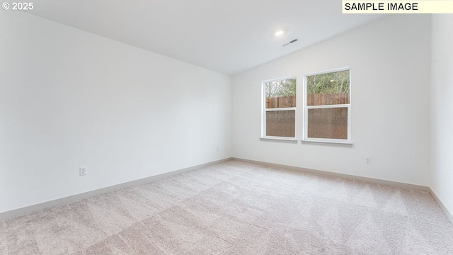 unfurnished room featuring baseboards, visible vents, vaulted ceiling, and light colored carpet