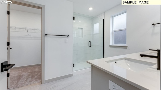 bathroom with a shower stall, a spacious closet, baseboards, and vanity