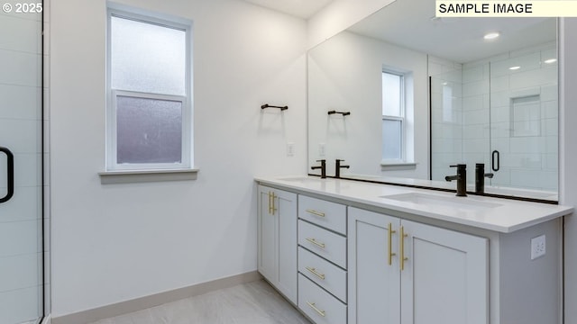 full bathroom with a shower stall, double vanity, a sink, and baseboards