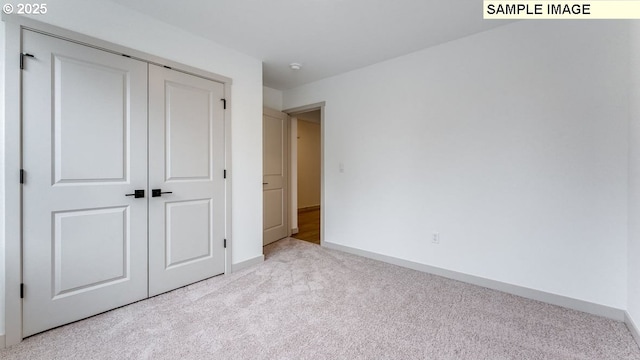 unfurnished bedroom with a closet, light carpet, and baseboards