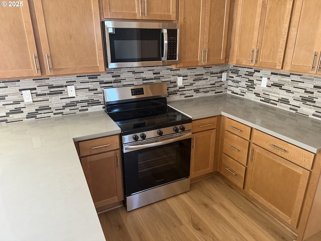6050 SE 136th Ave, Portland, OR 97236 - kitchen with light countertops, stainless steel appliances, light wood-style flooring, and backsplash