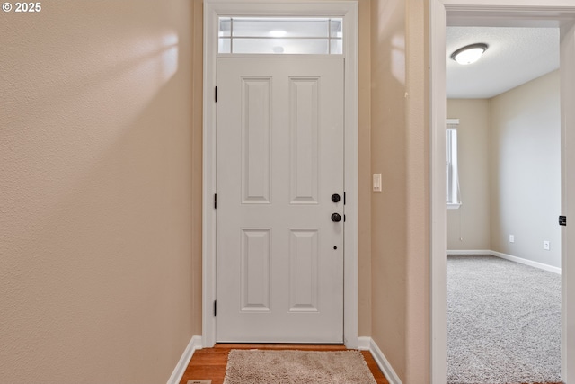 entryway featuring a textured ceiling, light wood finished floors, and baseboards