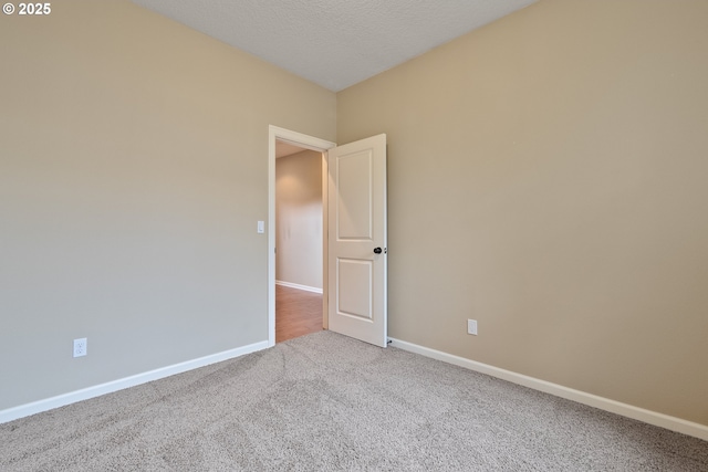 carpeted spare room featuring baseboards and a textured ceiling