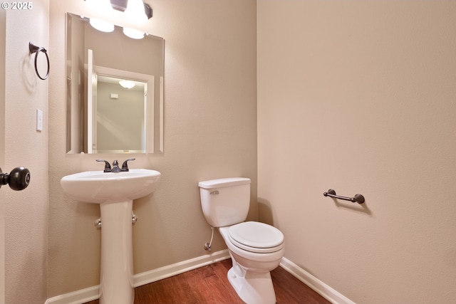 bathroom featuring a sink, toilet, baseboards, and wood finished floors