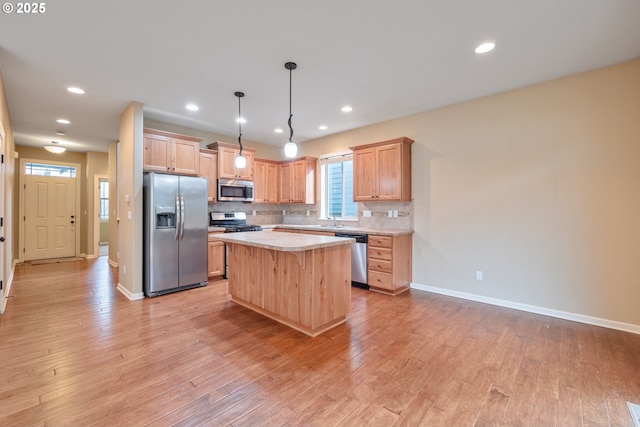 kitchen featuring light wood-style flooring, stainless steel appliances, a sink, light countertops, and tasteful backsplash