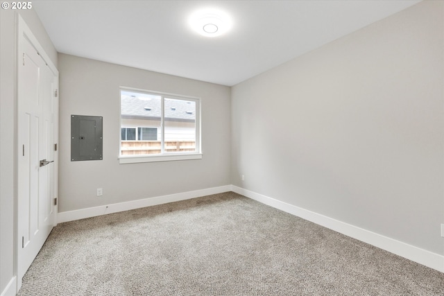 empty room featuring electric panel, baseboards, and carpet flooring