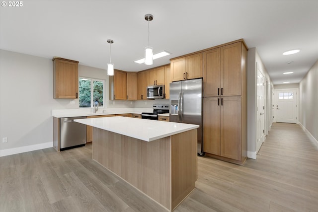 kitchen featuring a center island, decorative light fixtures, light countertops, light wood-style flooring, and appliances with stainless steel finishes