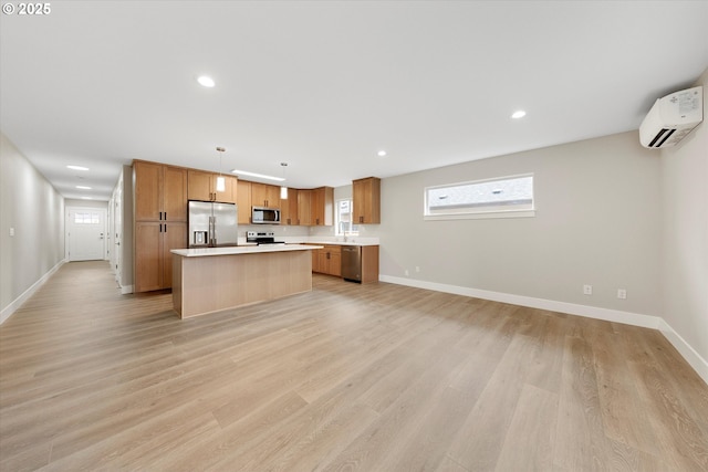 kitchen with a center island, stainless steel appliances, light countertops, pendant lighting, and a wall mounted AC