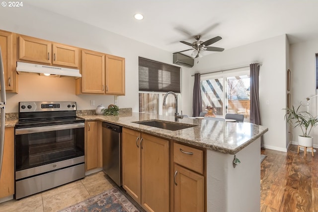 kitchen featuring sink, stainless steel appliances, light stone counters, kitchen peninsula, and an AC wall unit