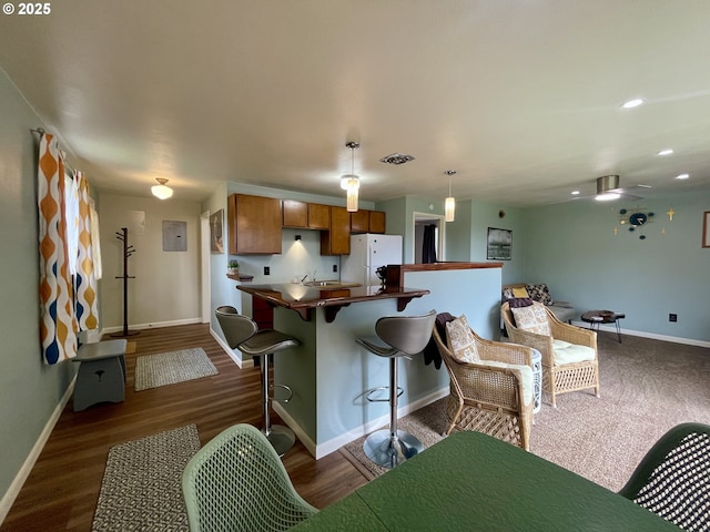 54825 Robinson Rd, Coquille, OR 97423 - kitchen featuring freestanding refrigerator, brown cabinetry, baseboards, dark wood-type flooring, and dark countertops