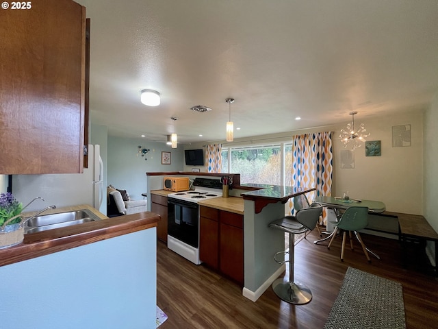 54825 Robinson Rd, Coquille, OR 97423 - kitchen with white appliances, a sink, dark wood-style floors, a breakfast bar area, and a chandelier