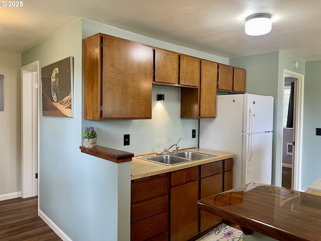 54825 Robinson Rd, Coquille, OR 97423 - kitchen with a sink, freestanding refrigerator, baseboards, dark wood-style flooring, and brown cabinetry