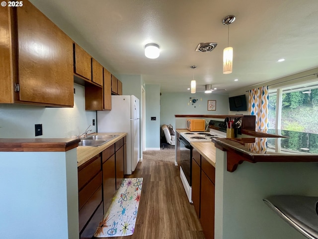 54825 Robinson Rd, Coquille, OR 97423 - kitchen featuring white appliances, a sink, dark wood-style flooring, brown cabinetry, and pendant lighting