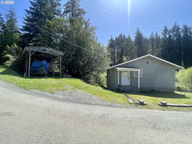 54825 Robinson Rd, Coquille, OR 97423 - view of front facade featuring a detached carport, board and batten siding, and a front lawn