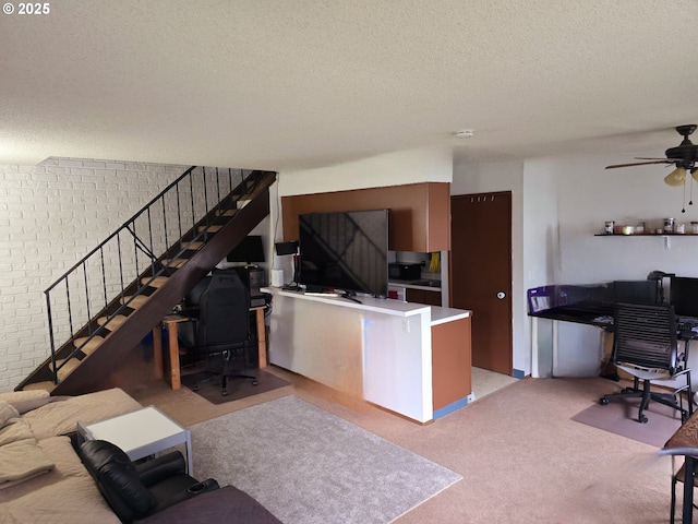 interior space with brick wall, ceiling fan, a textured ceiling, and light colored carpet