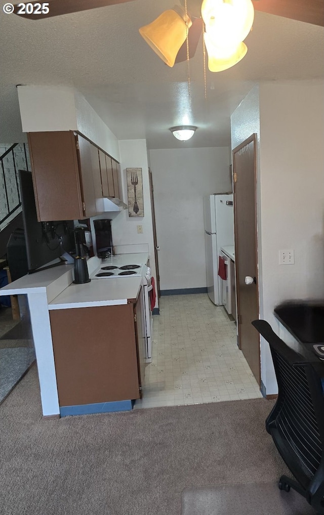 kitchen with light carpet, a peninsula, white appliances, light countertops, and light floors