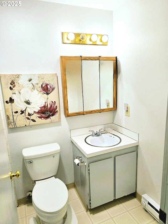 half bathroom with toilet, a baseboard heating unit, vanity, baseboards, and tile patterned floors