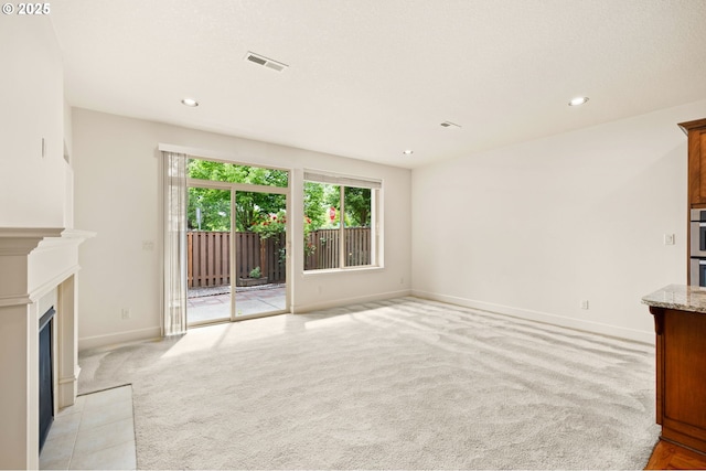 unfurnished living room featuring light carpet, a fireplace with flush hearth, baseboards, and recessed lighting