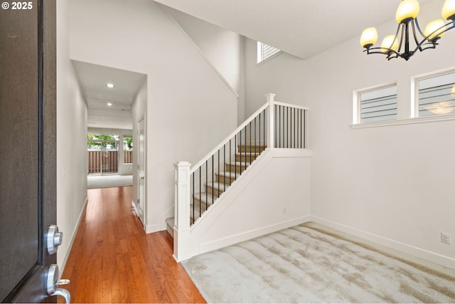 staircase with a chandelier, wood finished floors, baseboards, and recessed lighting