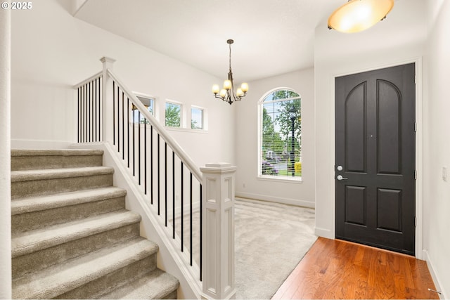 foyer entrance with a chandelier, stairs, baseboards, and light wood-style flooring