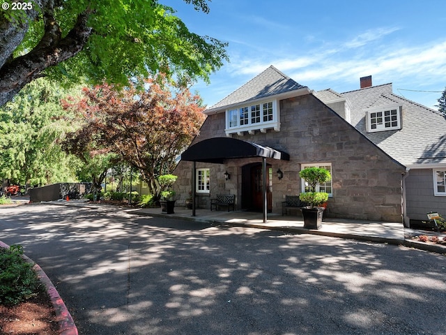 13920 Shireva Dr, Lake Oswego, OR 97034 - view of front of property with stone siding, a chimney, a patio area, and a shingled roof