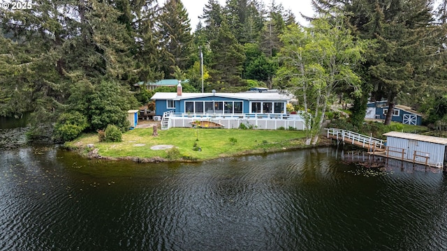 back of house featuring a water view, a storage shed, an outdoor structure, and a wooded view