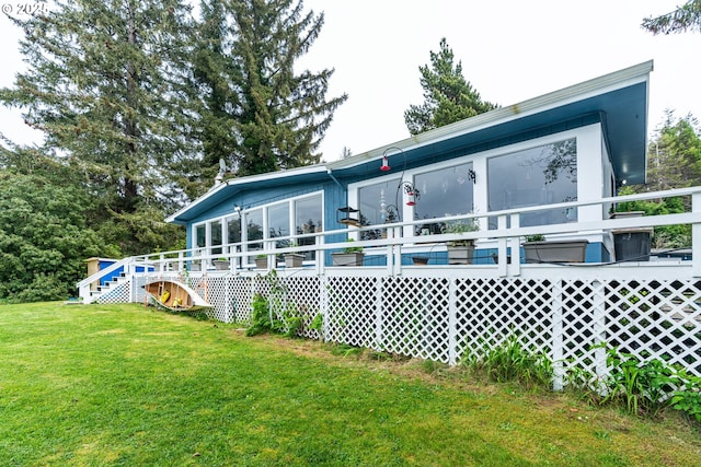 rear view of property with a lawn, a sunroom, stairs, and a wooden deck