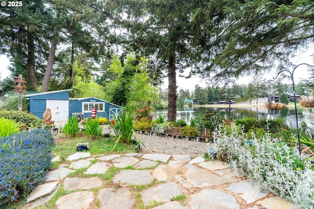 view of yard featuring an outdoor structure, a water view, and a storage shed