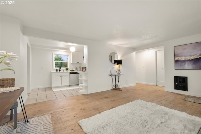 living room featuring sink, heating unit, and light wood-type flooring