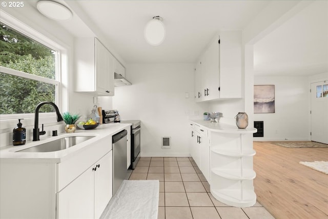 kitchen featuring light tile patterned flooring, appliances with stainless steel finishes, sink, and white cabinets