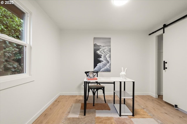 office with a barn door and light hardwood / wood-style floors