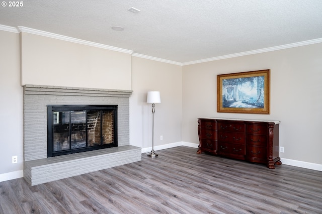 unfurnished living room featuring a brick fireplace, crown molding, and wood finished floors