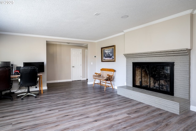 home office featuring a fireplace, ornamental molding, a textured ceiling, wood finished floors, and baseboards