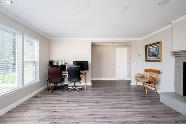 home office featuring crown molding, light hardwood / wood-style floors, a textured ceiling, and a brick fireplace