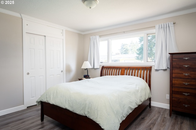 bedroom with a closet, crown molding, baseboards, and wood finished floors